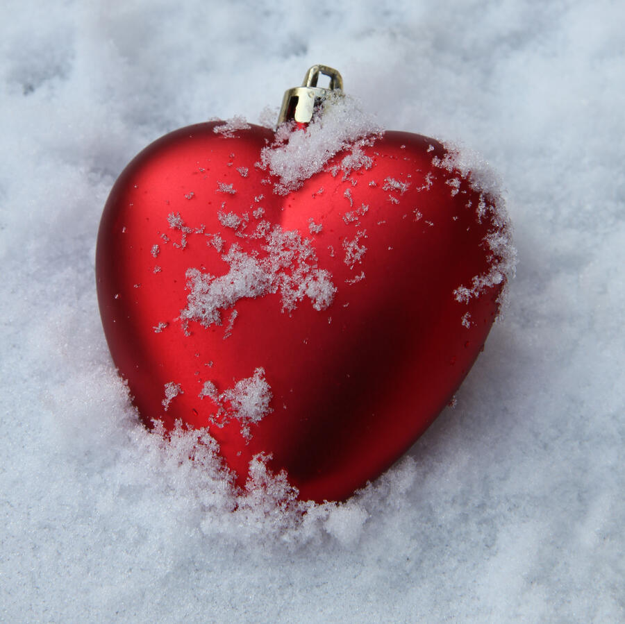 Red heart shaped Christmas ornament in the fresh snow