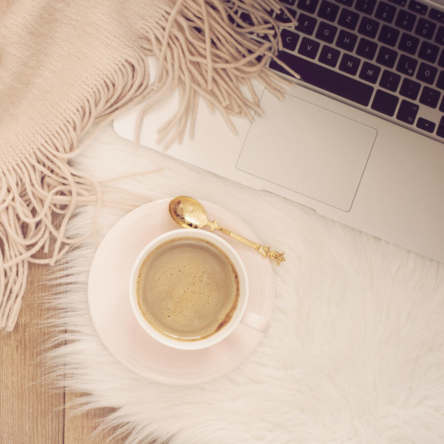 Cozy winter telehealth setup with blanket, cup of coffee, and laptop