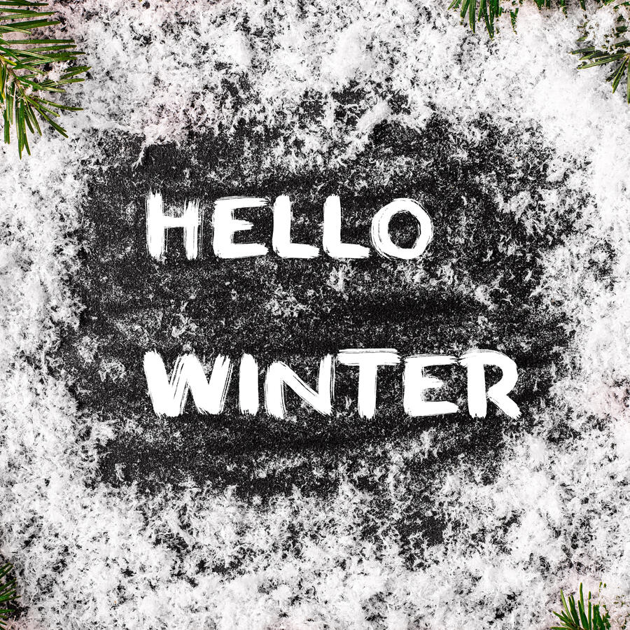 Hello Winter text on black background surrounded by snow